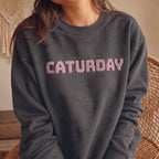 Woman wearing charcoal Caturday cat lover sweatshirt with raised pink puff lettering