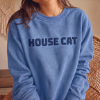 Woman wearing Carolina blue HOUSE CAT puff print sweatshirt, a cozy unisex cat lover crewneck with raised navy lettering and casual everyday style.