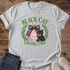 Feminine Cat Shirt Aesthetic Graphic Tee Design Black Cat With Green Eyes Coquette Style Fashion Statement Perfume Bottle Art Detail Pink Bow Accent Laurel Wreath Frame Cat Lover Gift Casual Wear Essential Soft Girl Style Unique Design