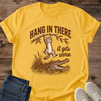 Daisy yellow Hang In There Gator cat T-shirt with vintage tabby above an alligator and “It gets worse” sarcastic graphic