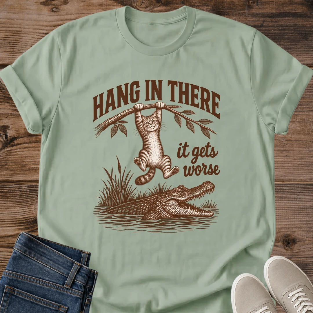 Sage green Hang In There Gator cat T-shirt with vintage tabby above an alligator and “It gets worse” sarcastic graphic