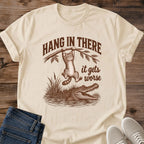 Sand Hang In There Gator cat T-shirt with vintage tabby above an alligator and “It gets worse” sarcastic graphic