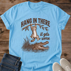 Sky blue Hang In There Gator cat T-shirt with vintage tabby above an alligator and “It gets worse” sarcastic graphic