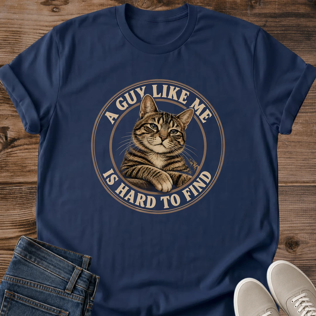 Navy T-shirt flat lay featuring a brown tabby with crossed front paws inside a tan circular border reading A Guy Like Me Is Hard to Find.
