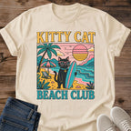 Graphic Cat Tee Retro Beach Design Vintage Surf Club Shirt Unisex White Cotton Apparel Black Cat Illustration Bold Pink Sunglasses Teal Surfboard Graphics Sunset Color Palette Summer Beach Theme Funny Cat Lover Gift Casual Wear Collection