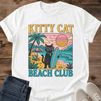 Retro Beach Shirt Vintage Surf Club Design Cat Graphic Tee Unisex White Cotton Shirt Black Cat Illustration Pink Sunglasses Style Teal Surfboard Graphics Bold Sunset Colors Summer Casual Wear Funny Cat Lover Gift Beach Themed Apparel Soft