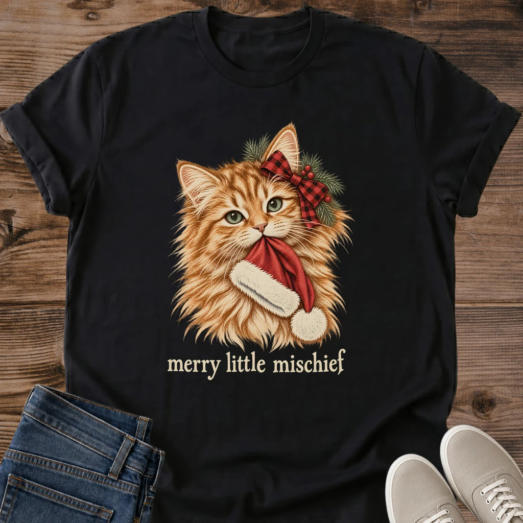 Black Merry Little Mischief Christmas cat T-shirt flat lay featuring an orange tabby with a red plaid bow holding a Santa hat.