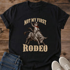 Not My First Rodeo Cat Shirt Black Funny Cowboy Cat Tee Tabby Cat Riding Bull Graphic Vintage Western Cat Shirt Rodeo Cat Tee Country Cat Lover Gift Cowgirl Cat Mom Shirt Cat In Cowboy Hat Gildan 64000 Softstyle Unisex Cat Whisker Co
