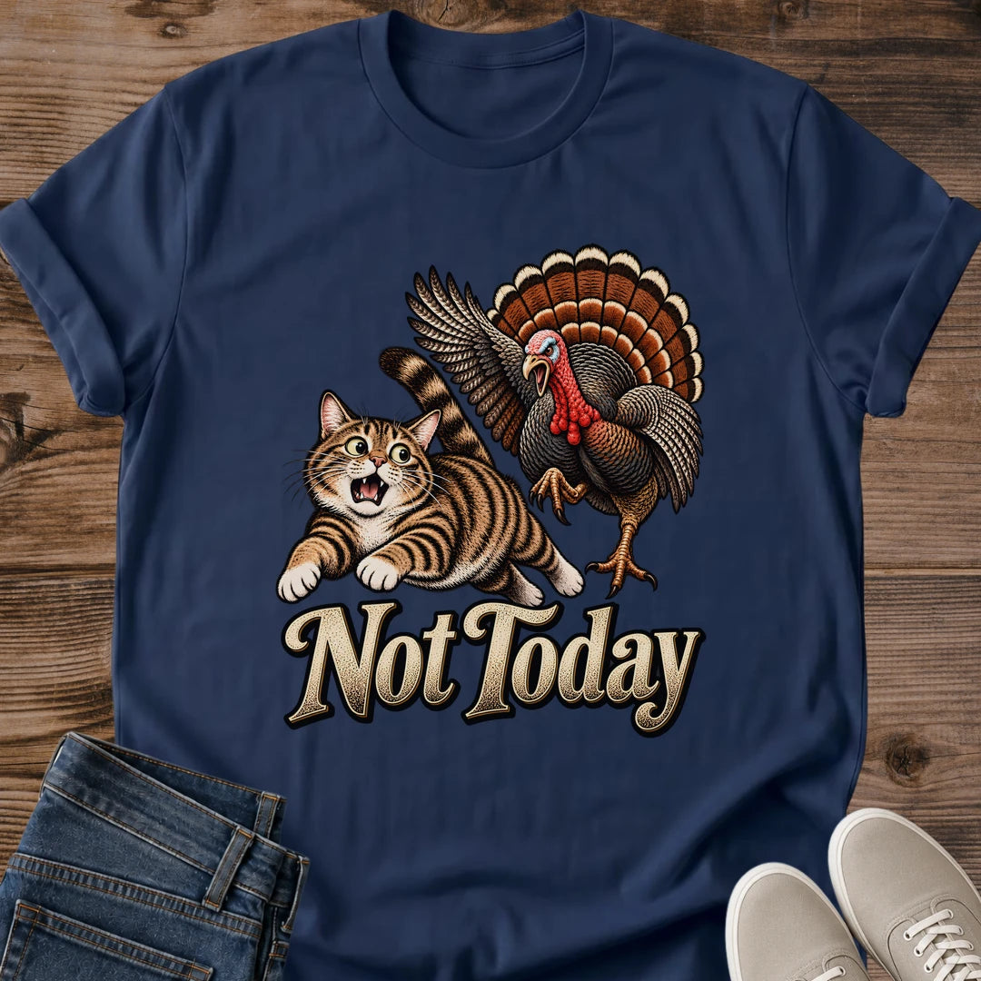 Navy blue Gildan 64000 unisex Thanksgiving cat T-shirt with a crew neck and rolled short sleeves, laid flat on rustic wooden planks beside folded jeans and light gray sneakers. A vintage brown tabby with raised paws and an open mouth runs from a turkey with spread wings and orange-brown tail feathers. Large cream "Not Today" lettering contrasts with the dark blue shirt.