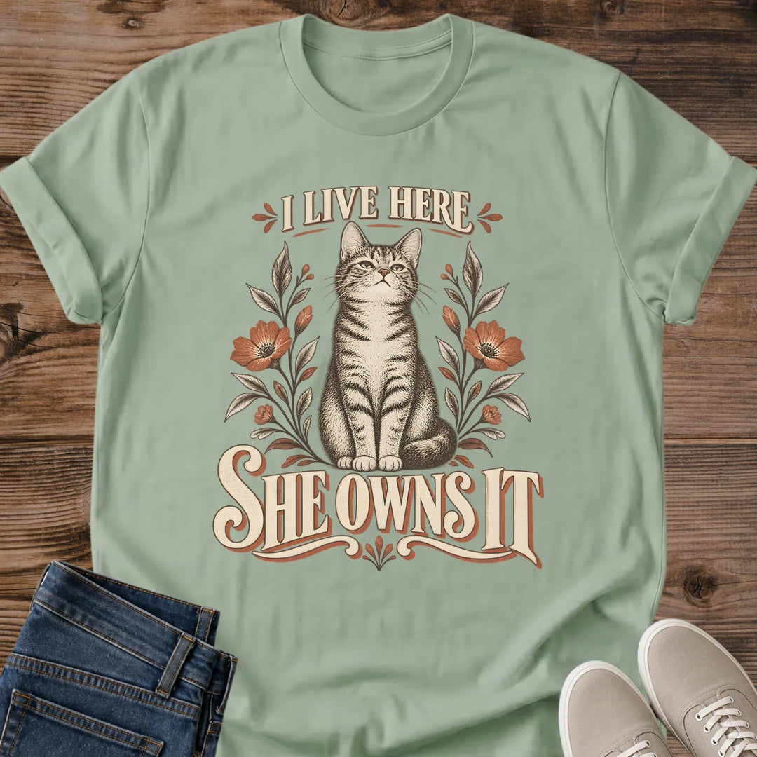 SageFunny Cat Home Shirt I Live Here She Owns It Floral Graphic Tee Gift Idea Ring Spun Cotton Soft Breathable Fabric Relaxed Unisex Fit Vintage Print Design Cat Person Apparel Casual Everyday Wear Statement Piece Great Gift