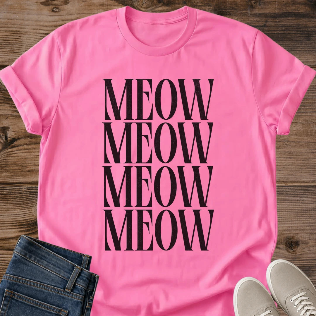 Azalea pink Gildan 64000 unisex Stacked Meow cat T-shirt shown from the front on rustic wooden planks. The bright pink crewneck tee features four stacked rows of "MEOW" in tall black uppercase serif lettering, forming a large minimalist cat typography print. Rolled short sleeves frame the shirt, with folded dark blue jeans at the lower left and light gray lace-up sneakers at the lower right.