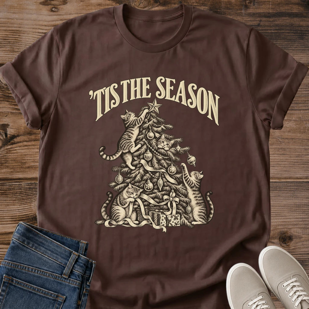 Dark Chocolate 'Tis the Season Christmas cat T-shirt flat lay with cream vintage-style artwork of cats climbing and playing in a decorated tree above gifts.