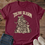 Maroon 'Tis the Season Christmas cat T-shirt flat lay with cream vintage-style artwork of cats climbing and playing in a decorated tree above gifts.