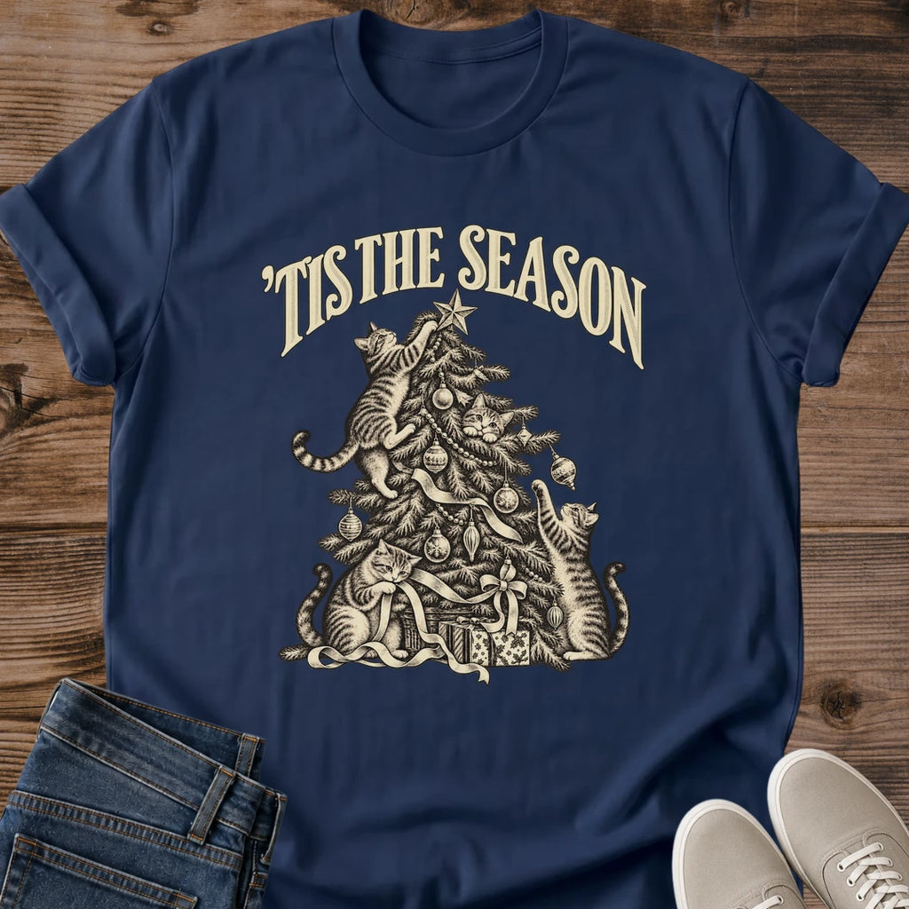 Navy 'Tis the Season Christmas cat T-shirt flat lay with cream vintage-style artwork of cats climbing and playing in a decorated tree above gifts.